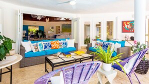 A bright living room with a blue sofa, wicker chairs, and a ceiling fan. - Unlimited Luxury Laureanne's Villa (La Romana)