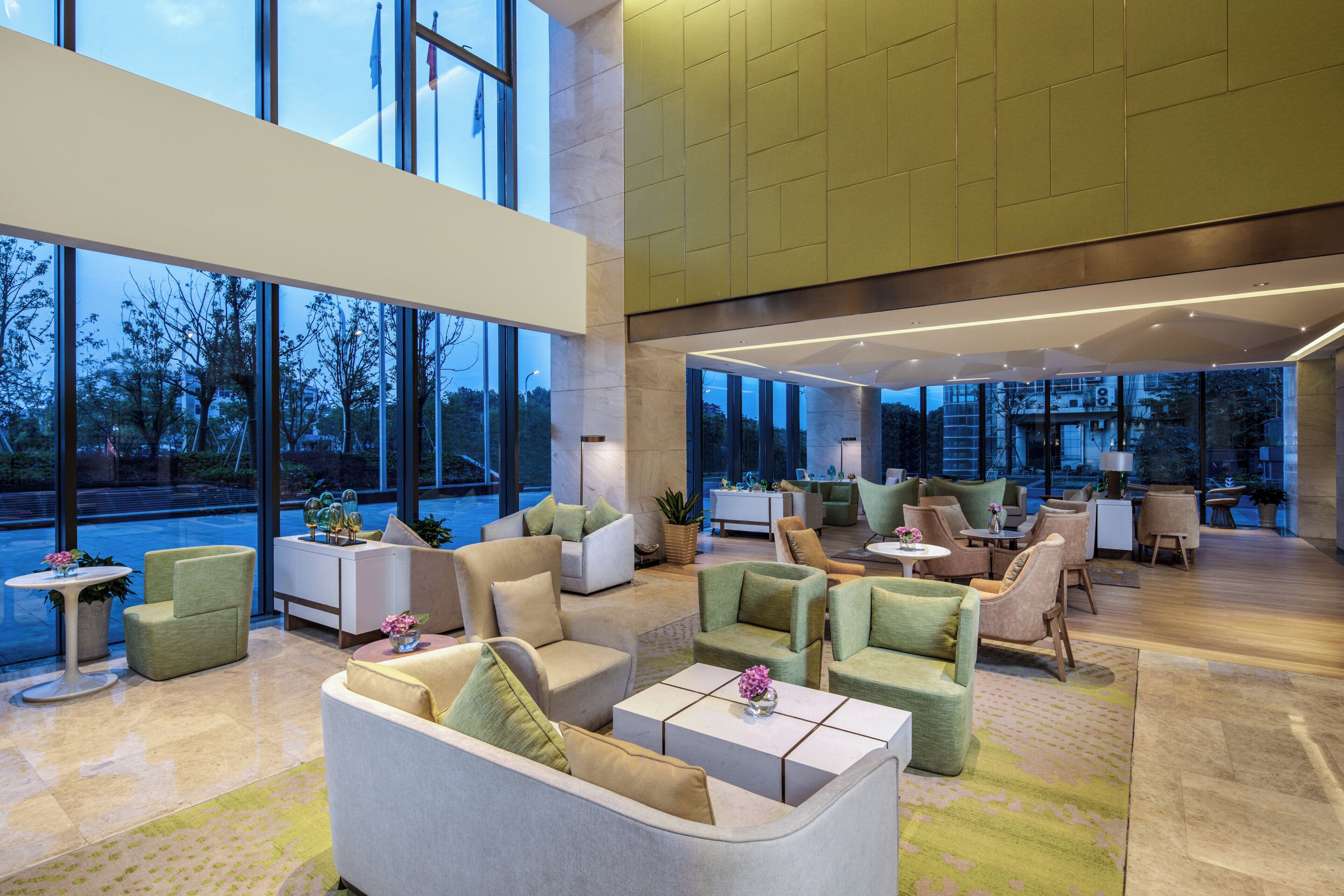 A spacious lobby with multiple seating areas, large windows, and a modern interior design.