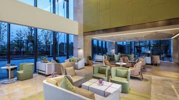 A spacious lobby with multiple seating areas, large windows, and a modern interior design.