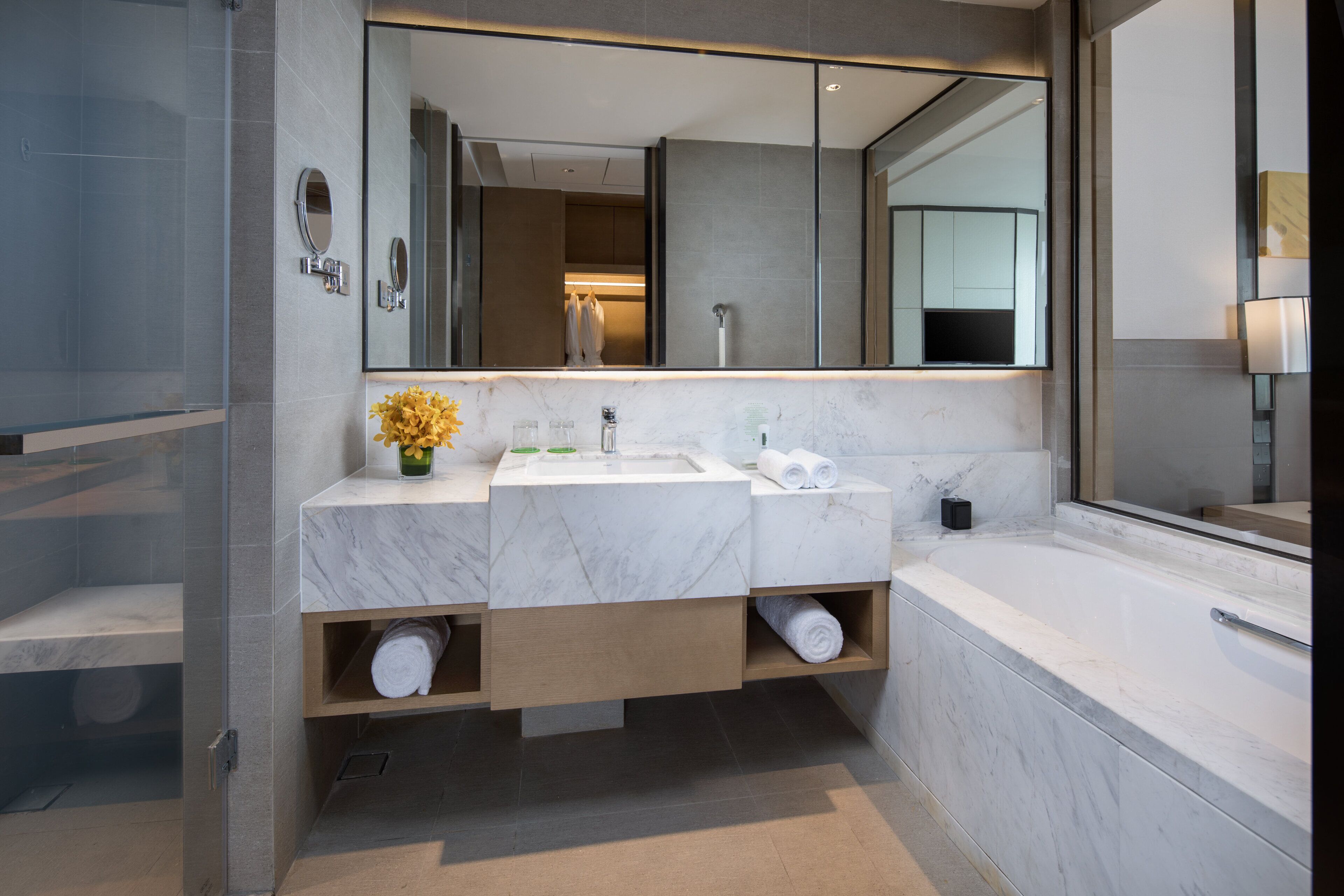 A modern bathroom with a double sink, a large mirror, and a bathtub.