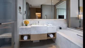 A modern bathroom with a double sink, a large mirror, and a bathtub.