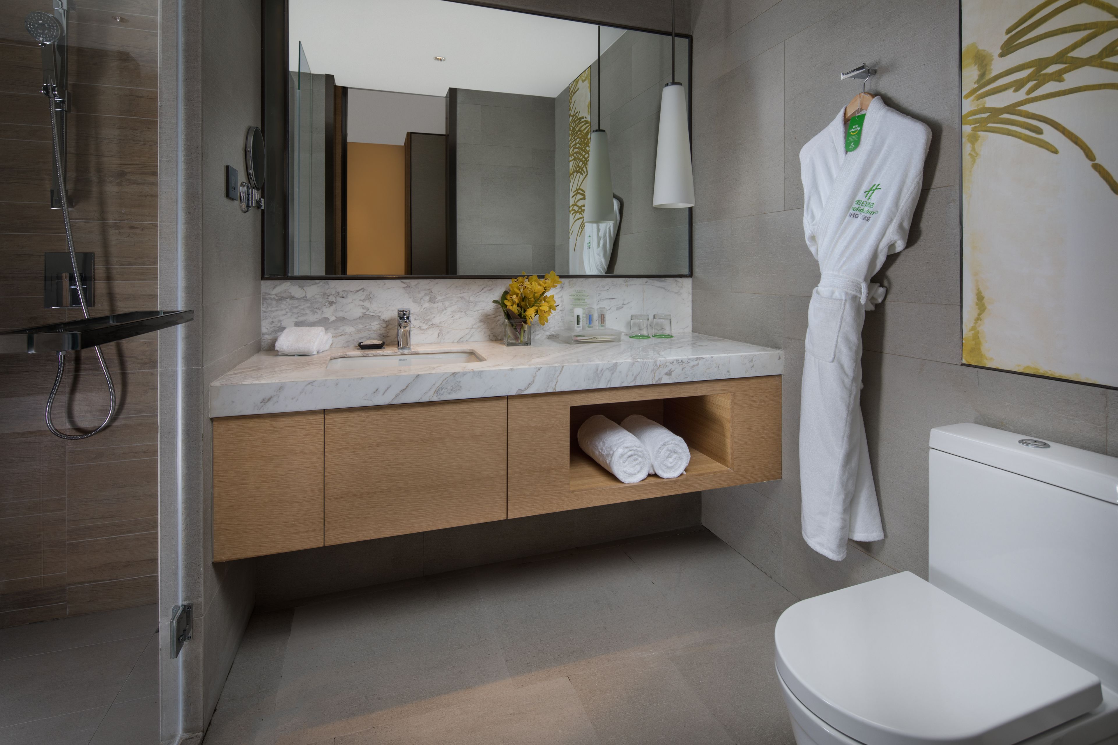 Un baño moderno con encimera de mármol, mueble de madera, inodoro blanco y un espejo grande.