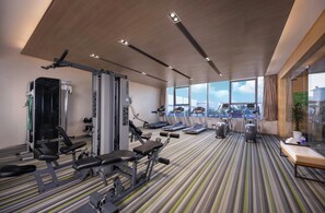 A modern gym with various exercise equipment, large windows, and a striped floor. - Holiday Inn Nanjing Harbour by IHG (Nanjing)
