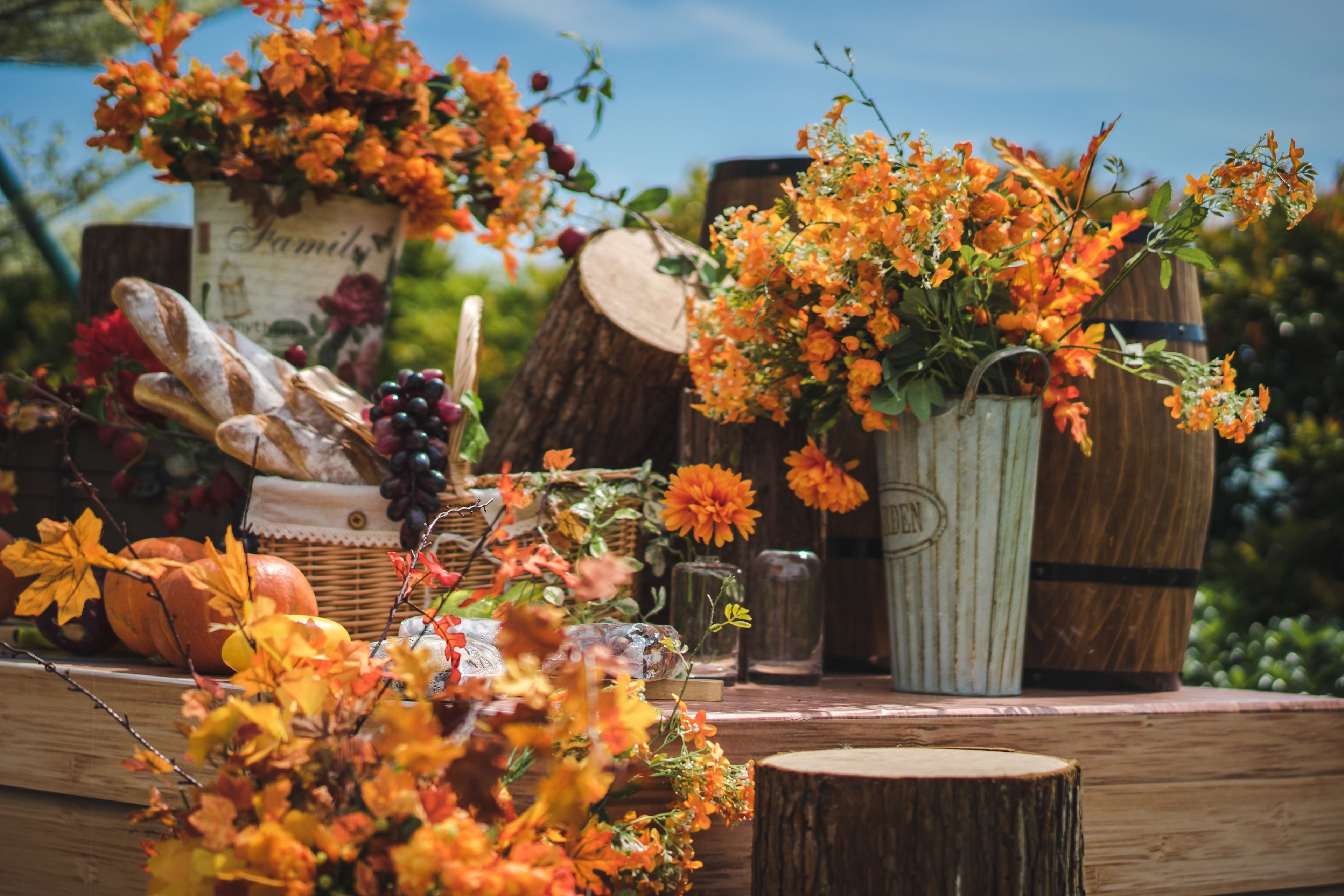 Une table en bois, dans un décor rustique, où l’on peut admirer une variété de fruits, de fleurs et de pains.