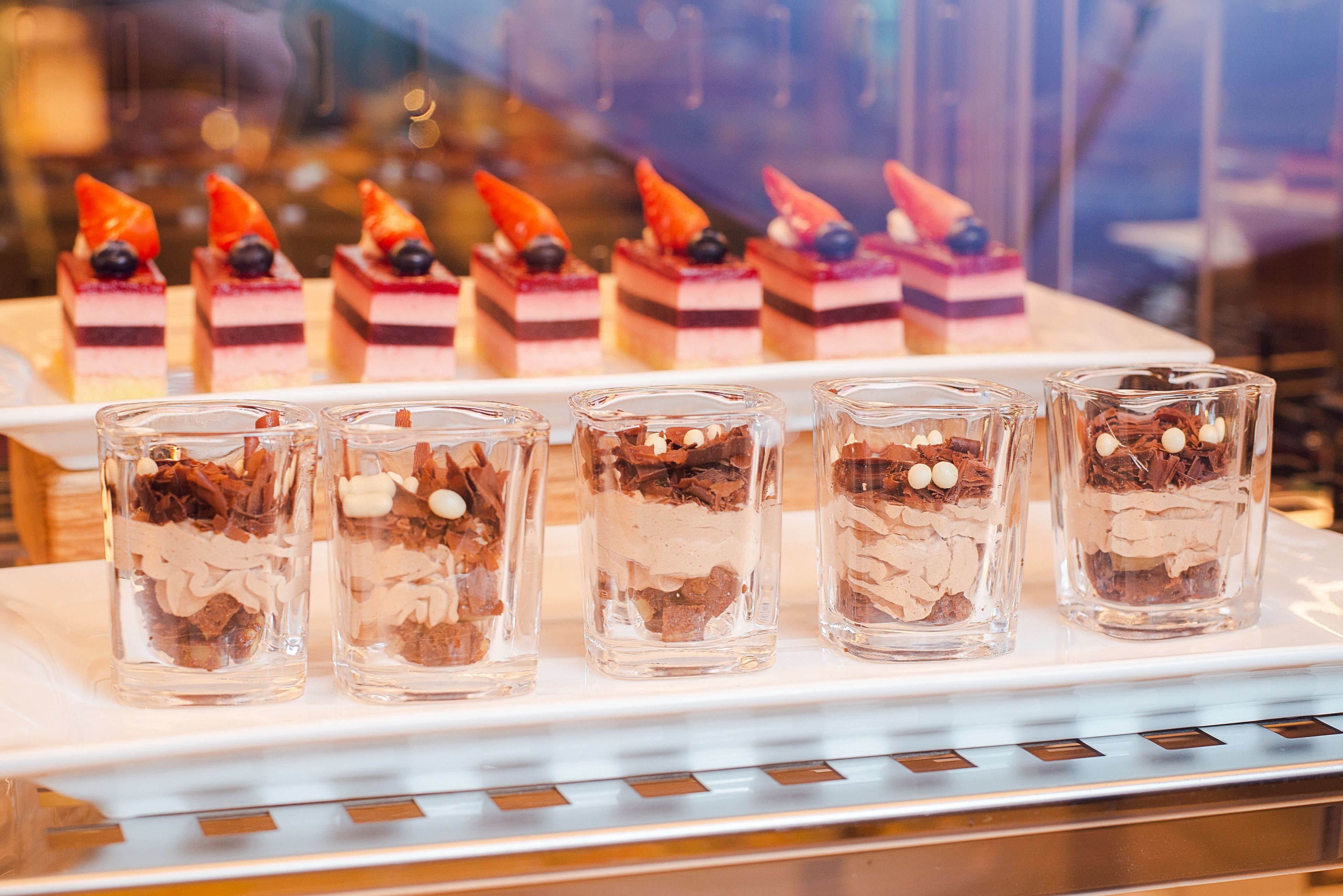 Exhibición de postres con pasteles en capas y mousse de chocolate en vasos de vidrio.