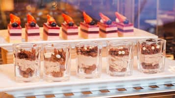 Exhibición de postres con pasteles en capas y mousse de chocolate en vasos de vidrio.