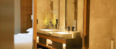 Une salle de bain moderne avec un grand miroir, deux lavabos et un espace douche.
