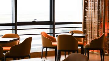 A restaurant with orange chairs and tables, large windows, and a wooden partition.