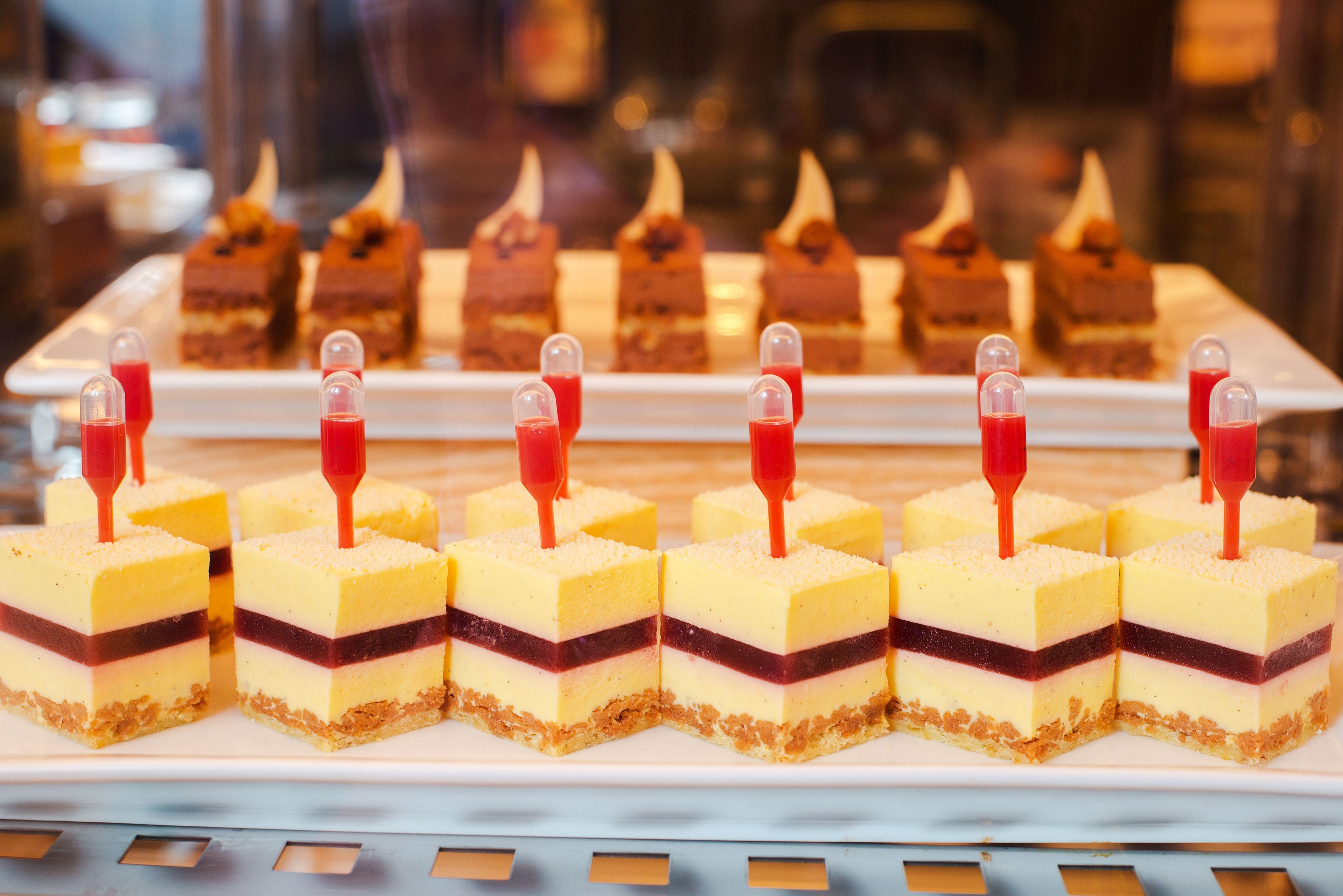 A dessert display with layered cakes and a glass dome on top.