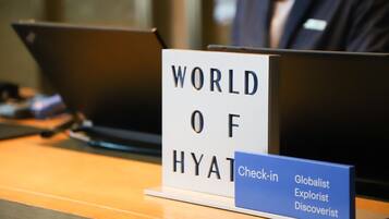 A check-in desk with a sign reading "WORLD OF HYATT" and a blue sign indicating "Check-in Globalist Explorer Discoverist."