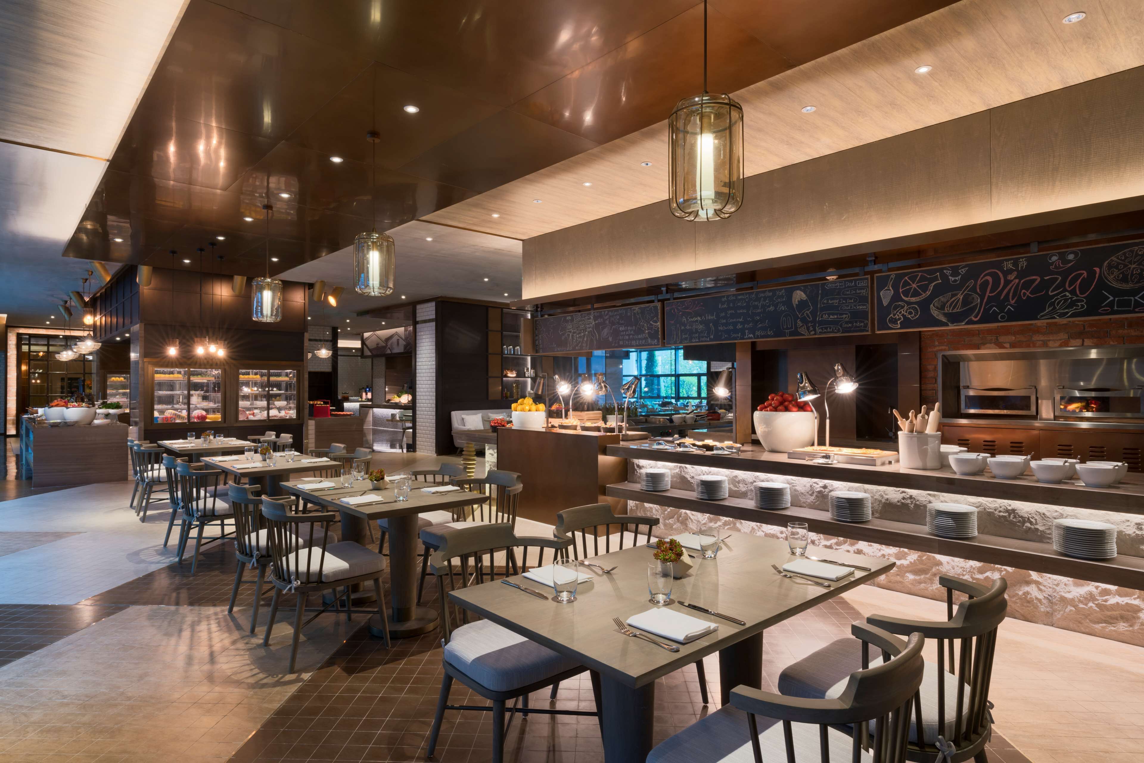 A modern restaurant with a bar area, dining tables, and a pizza menu on the wall.
