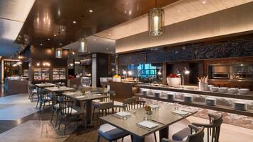 A modern restaurant with a bar area, dining tables, and a pizza menu on the wall.