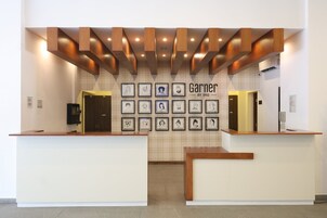 Un área de recepción con dos mostradores, una pared de retratos enmarcados y un cartel que dice "Garner by IHG".