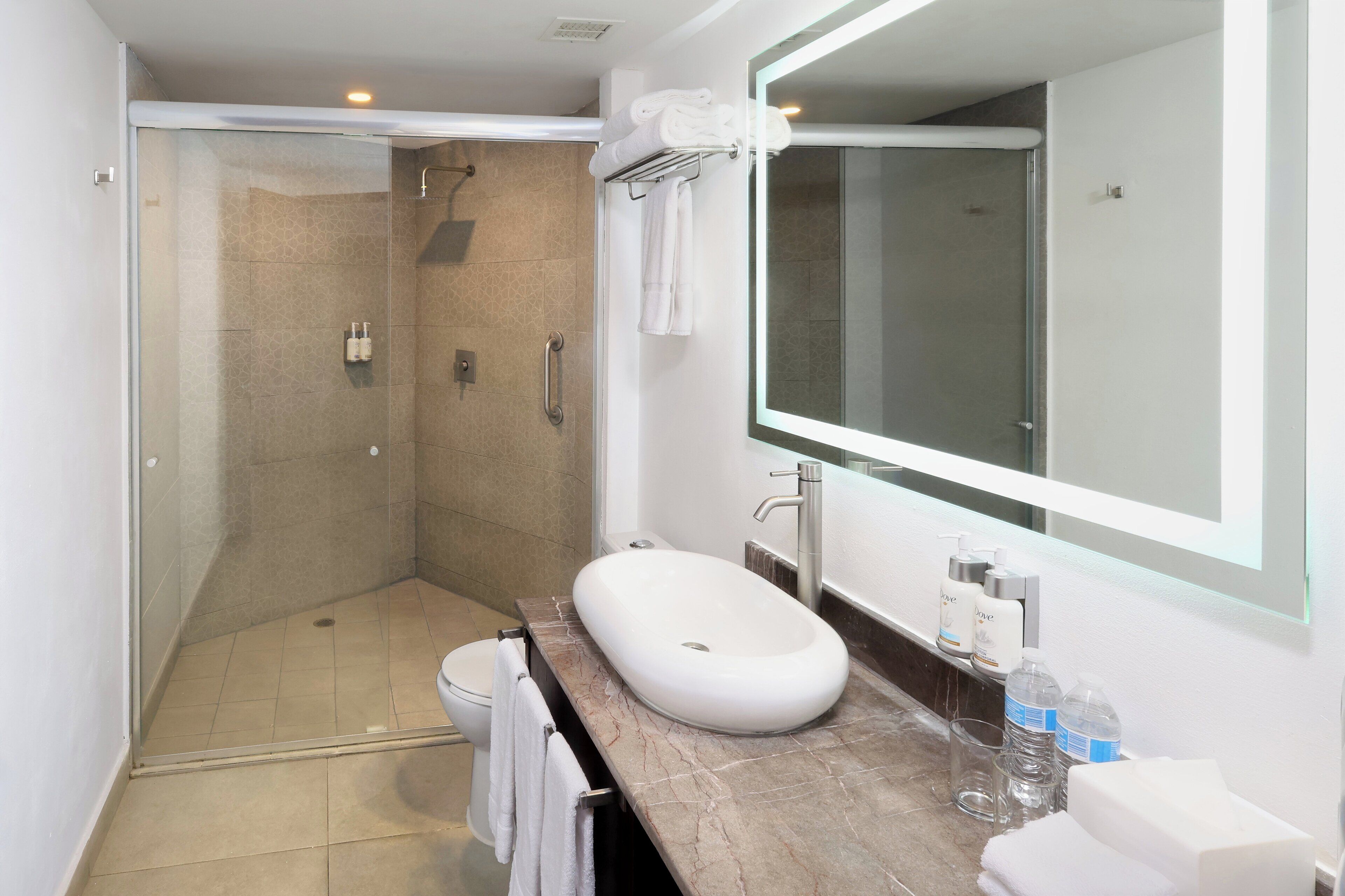 A modern bathroom with a glass-enclosed shower, a marble sink, and a large mirror.