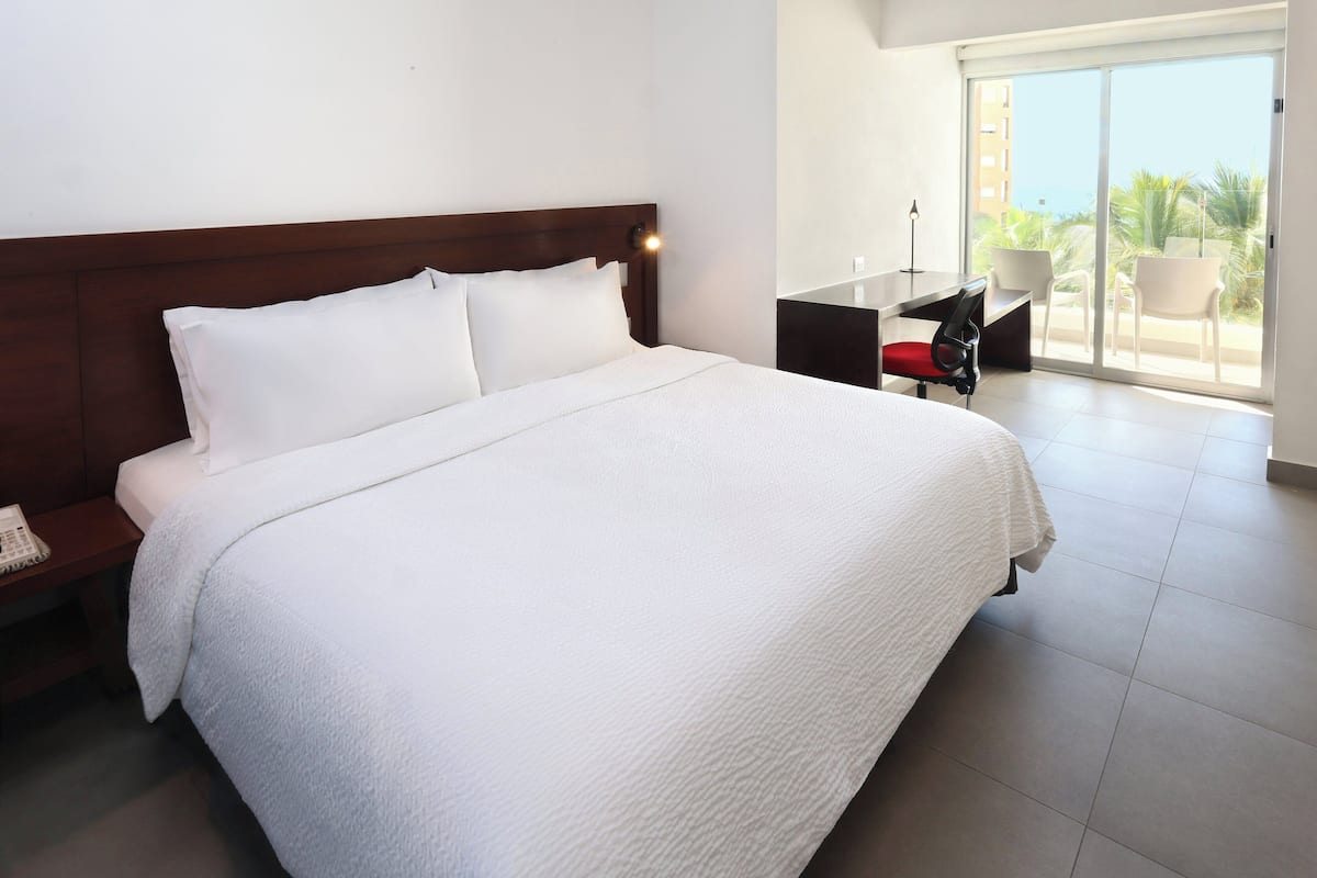 Habitación de hotel con una cama grande, un escritorio y vistas al exterior.
