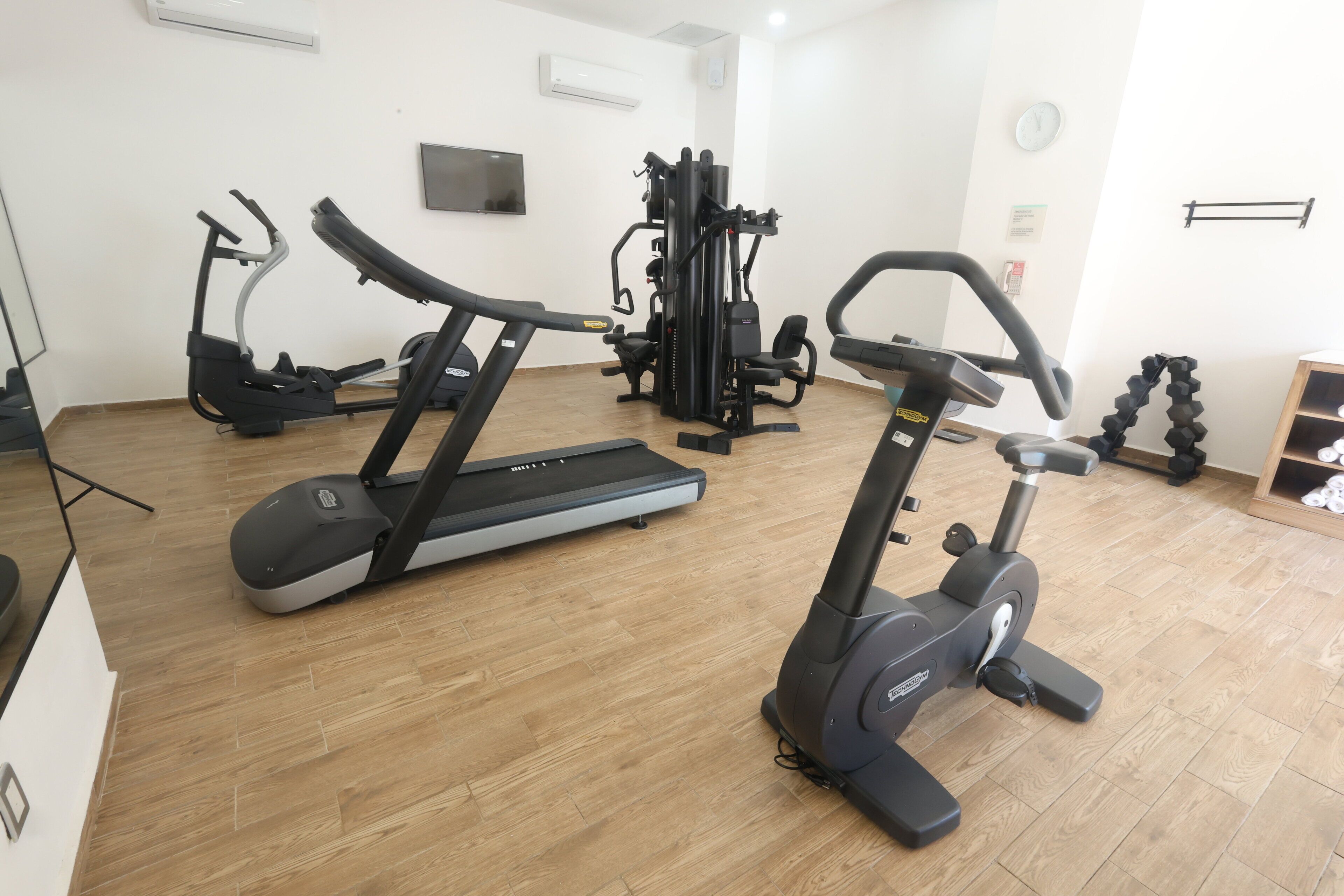 Un gimnasio con cintas de correr, elípticas y máquinas de pesas.