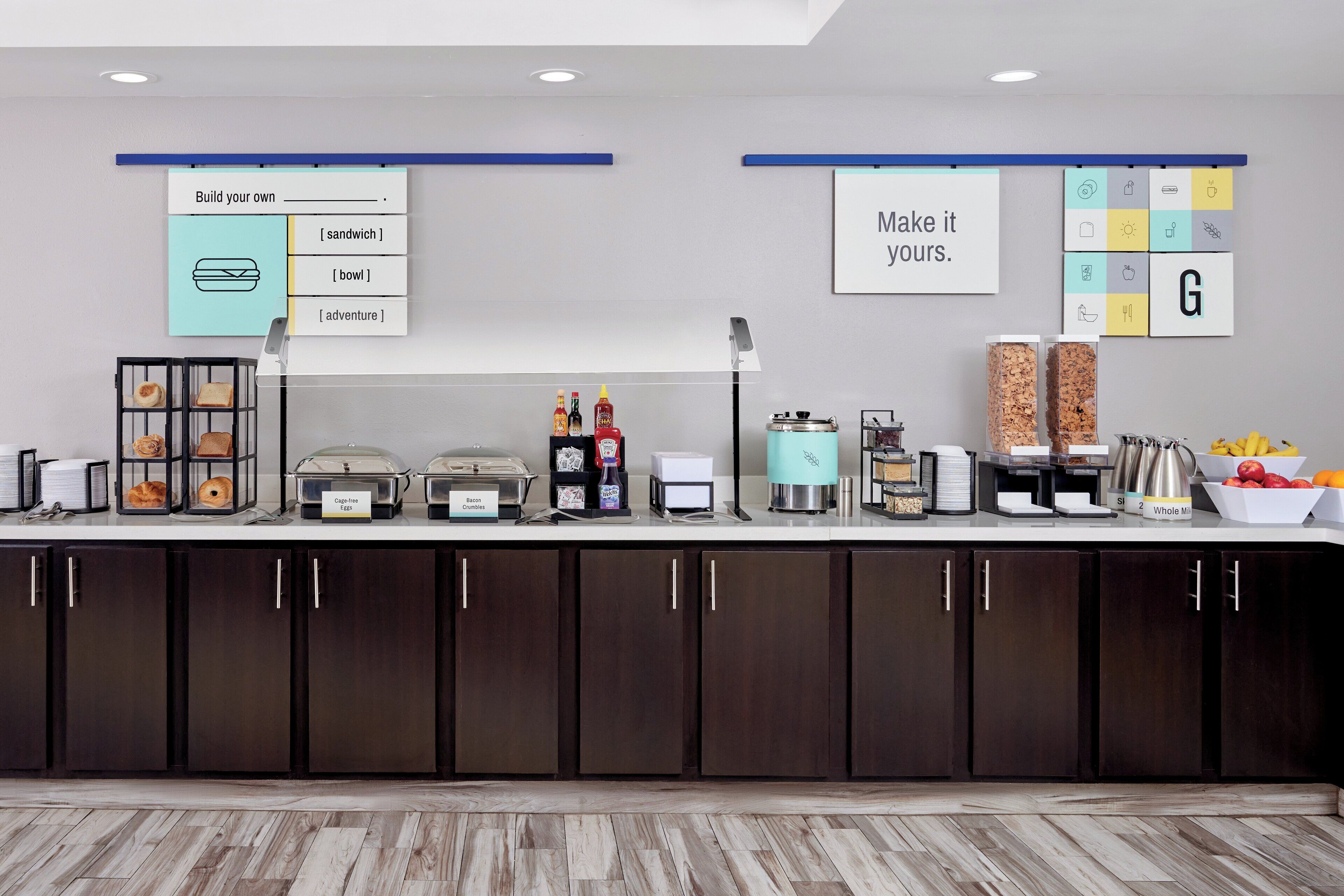 A buffet setup with labeled food stations, a coffee machine, and a fruit bowl.