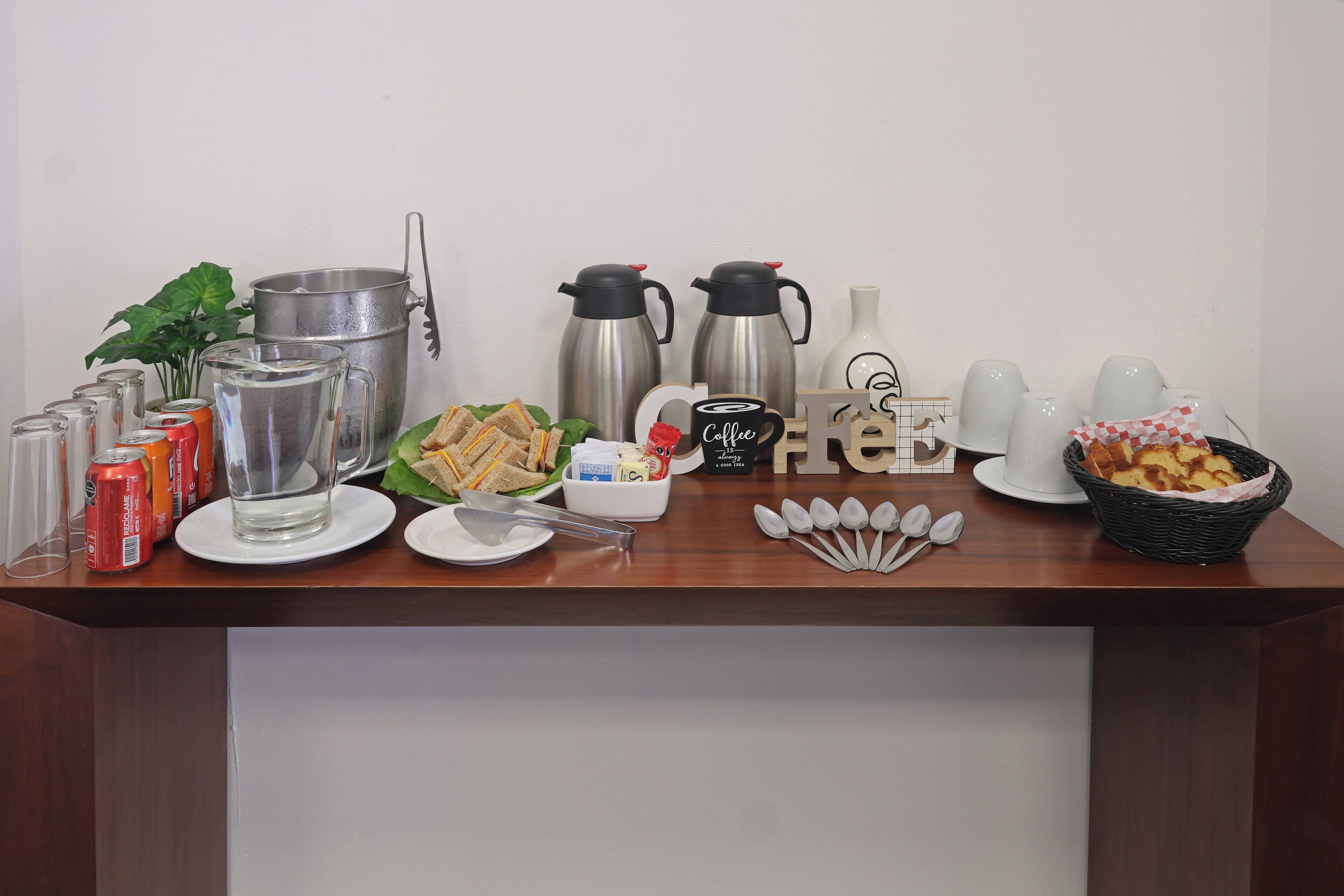 Disposición de un bufé de desayuno con diversos alimentos, cafeteras y utensilios.