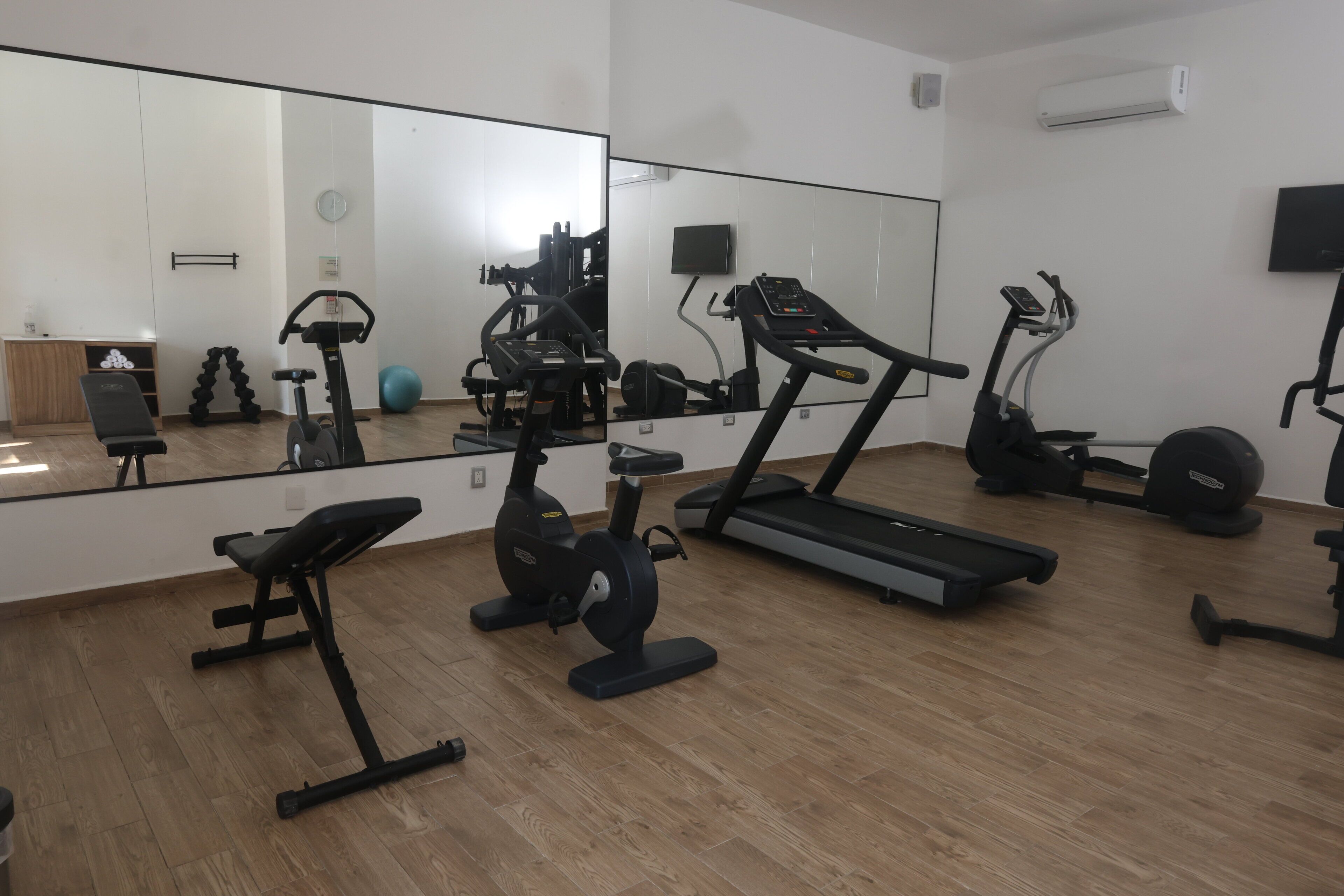 A gym with exercise equipment including a treadmill, stationary bike, and elliptical machine.
