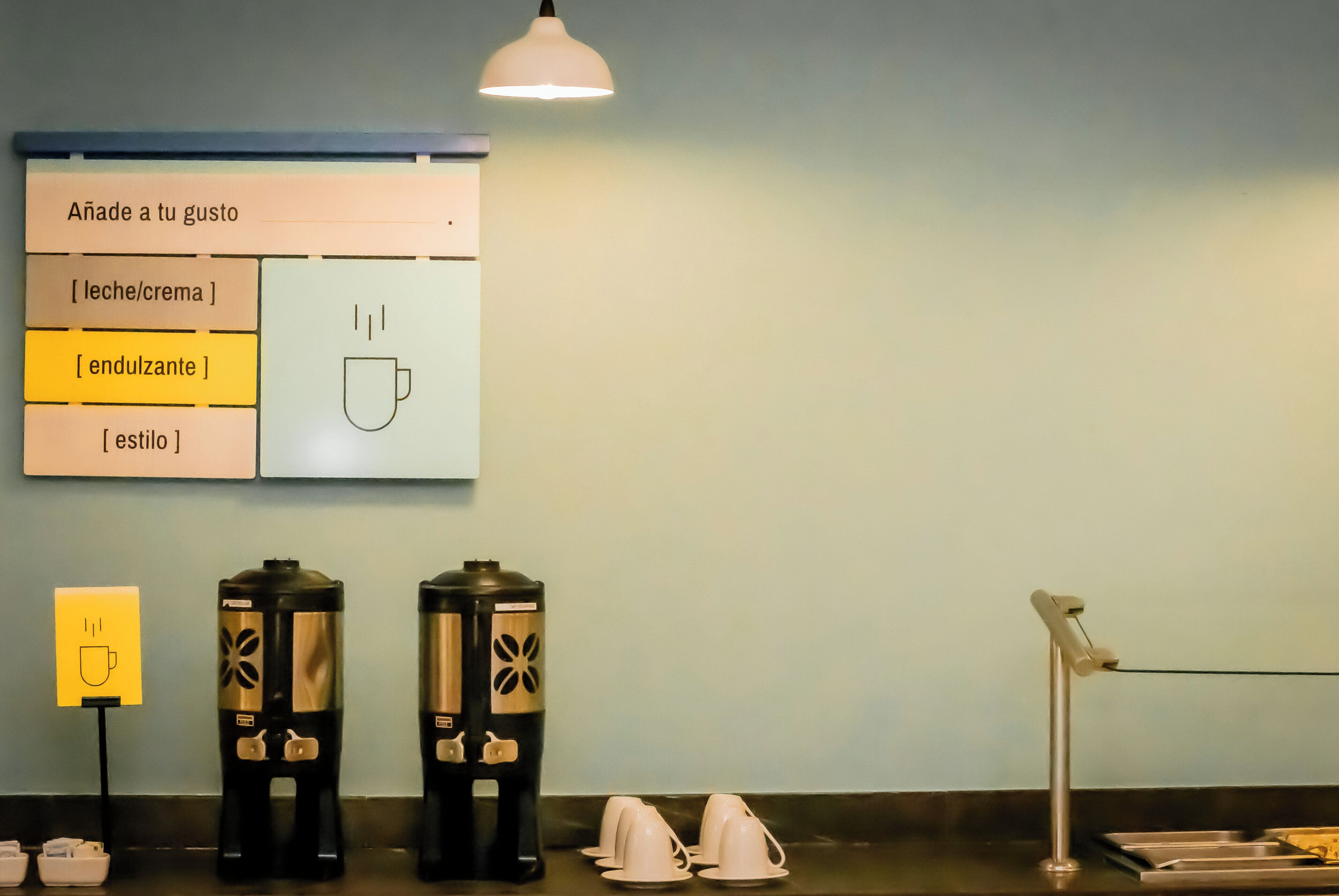A coffee station with a menu board, two coffee dispensers, and a coffee pot.
