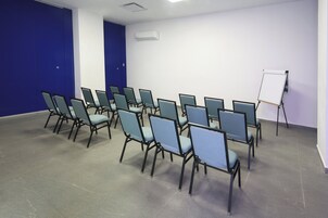 Un salón de conferencias con filas de sillas, una pizarra y una puerta.