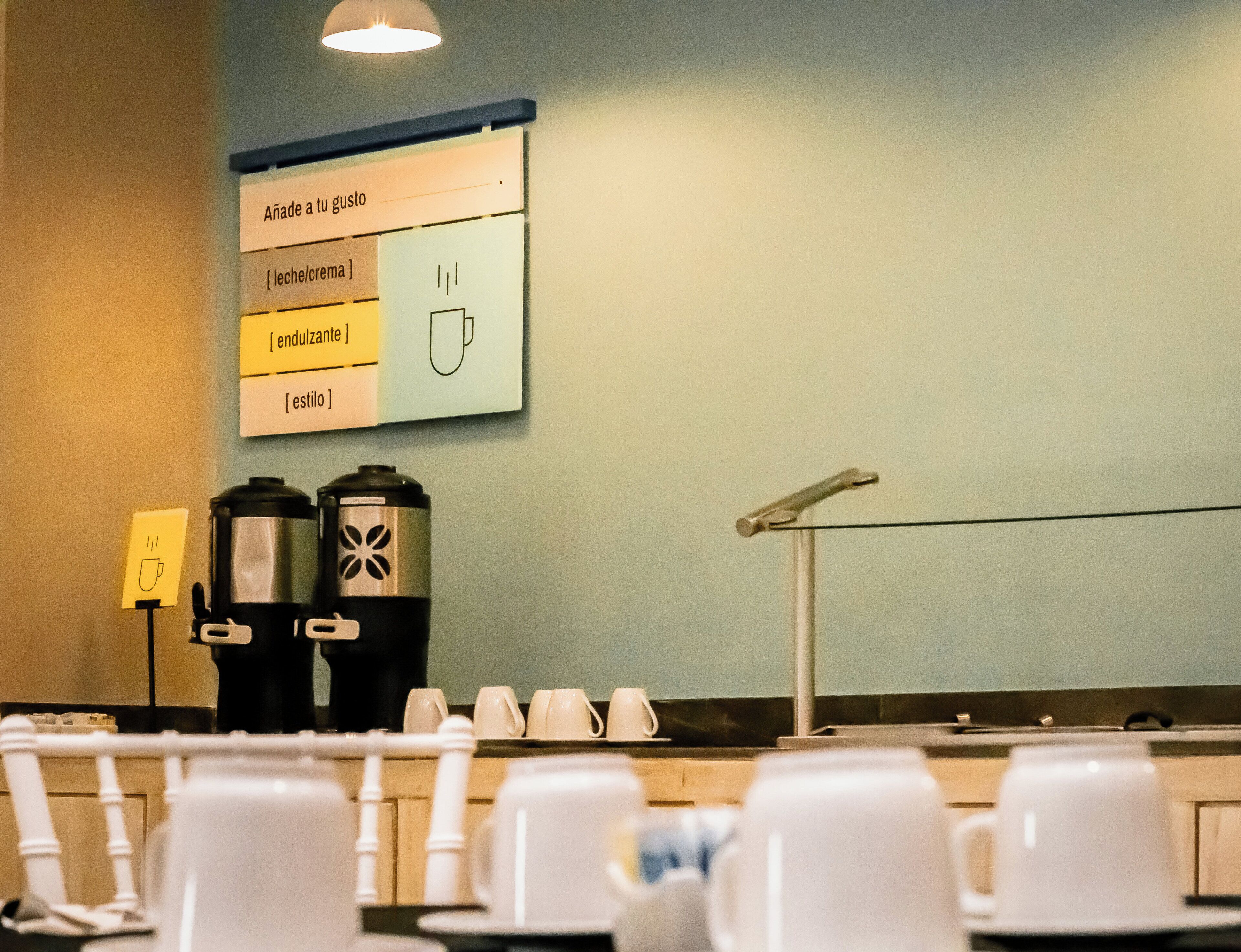 Una estación de café con un menú, dos cafeteras y varias tazas.