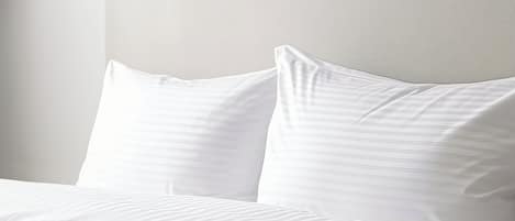 A neatly made bed with white linens and pillows.