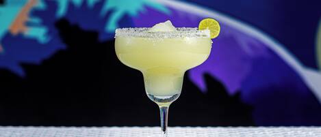 A margarita cocktail in a stemmed glass with a salted rim and a lime garnish, placed on a textured surface.