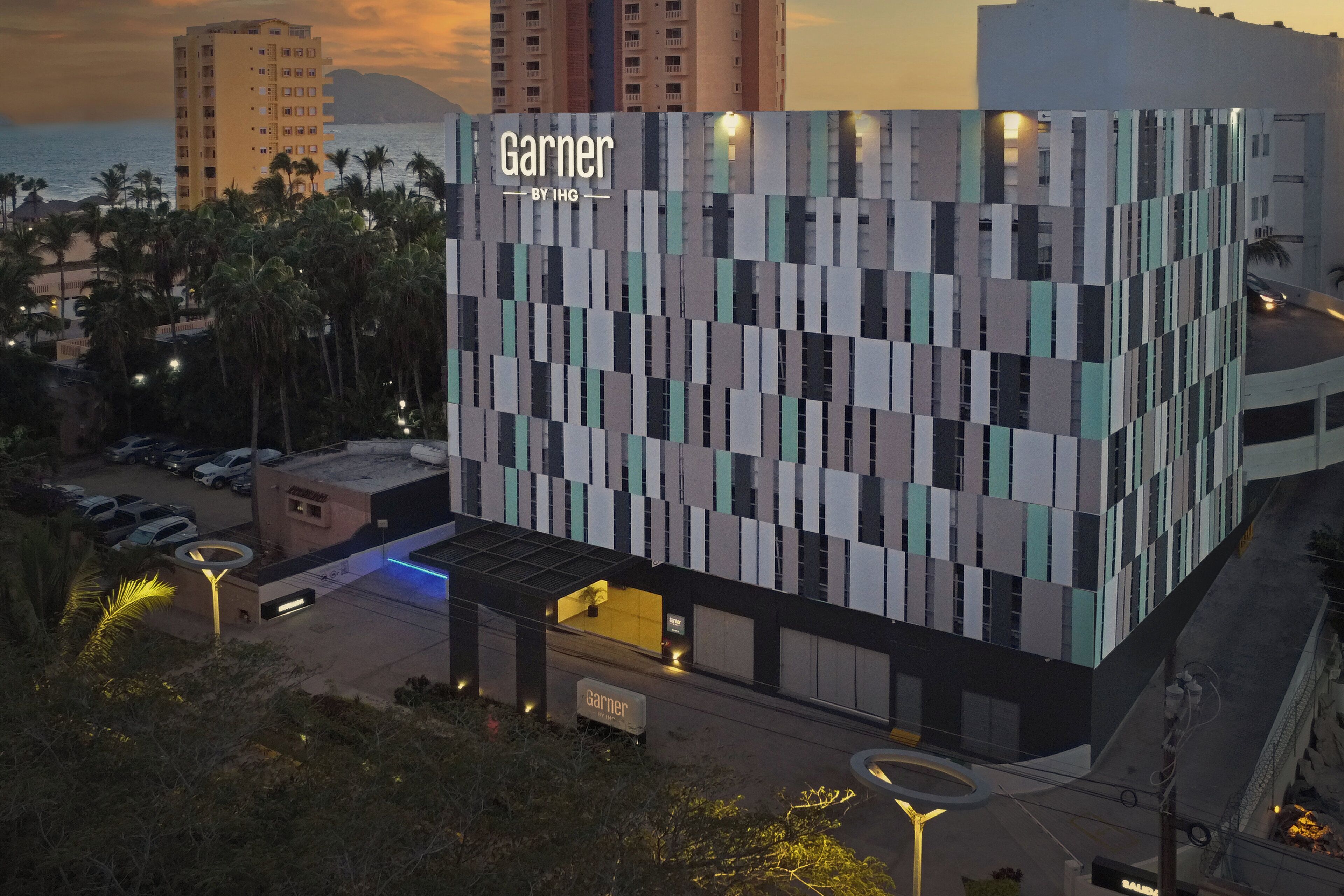 Un bâtiment moderne, orné d’une enseigne « Garner », entouré de palmiers et doté d’un parking.
