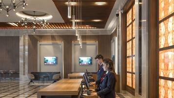 A modern hotel lobby with a reception desk, seating area, and large windows.