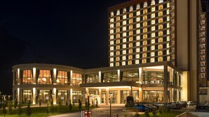 A multi-story hotel with a modern design, featuring a large glass facade and a well-lit entrance.