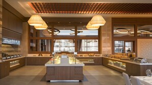 A modern kitchen with a central island, pendant lighting, and a view of the cityscape through large windows. - Ramada Plaza by Wyndham Rize (Rize)