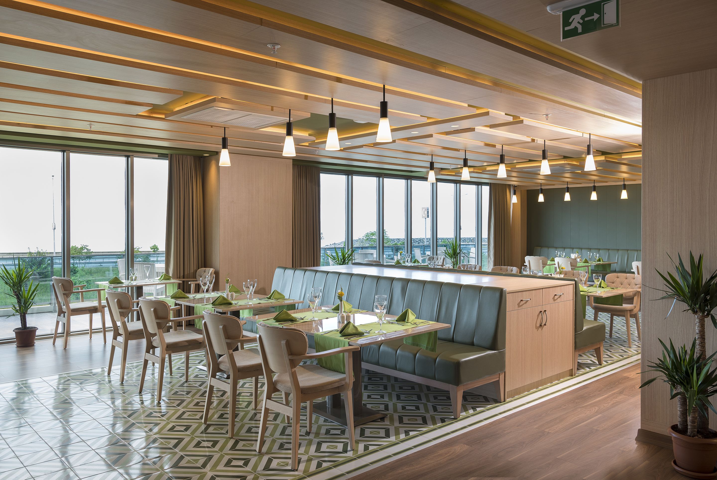 A modern restaurant with a bar, seating area, and large windows offering views.