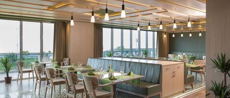 A modern restaurant with a bar, seating area, and large windows offering views.