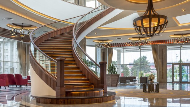 A modern hotel lobby with a spiral staircase, large windows, and contemporary lighting fixtures. - Ramada Plaza by Wyndham Rize (Rize)