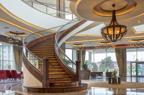 A modern hotel lobby with a spiral staircase, large windows, and contemporary lighting fixtures. - Ramada Plaza by Wyndham Rize (Rize)