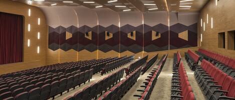 A theater with rows of red and black seats, wooden paneling, and geometric wall designs.