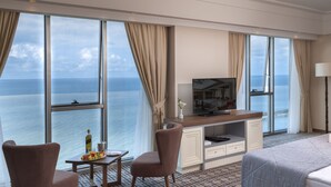 A hotel room with a large window, a desk, two chairs, a bed, and a TV. - Ramada Plaza by Wyndham Rize (Rize)