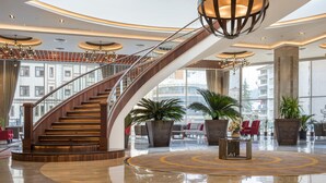 A spacious lobby with a grand staircase, large potted plants, and modern lighting fixtures. - Ramada Plaza by Wyndham Rize (Rize)