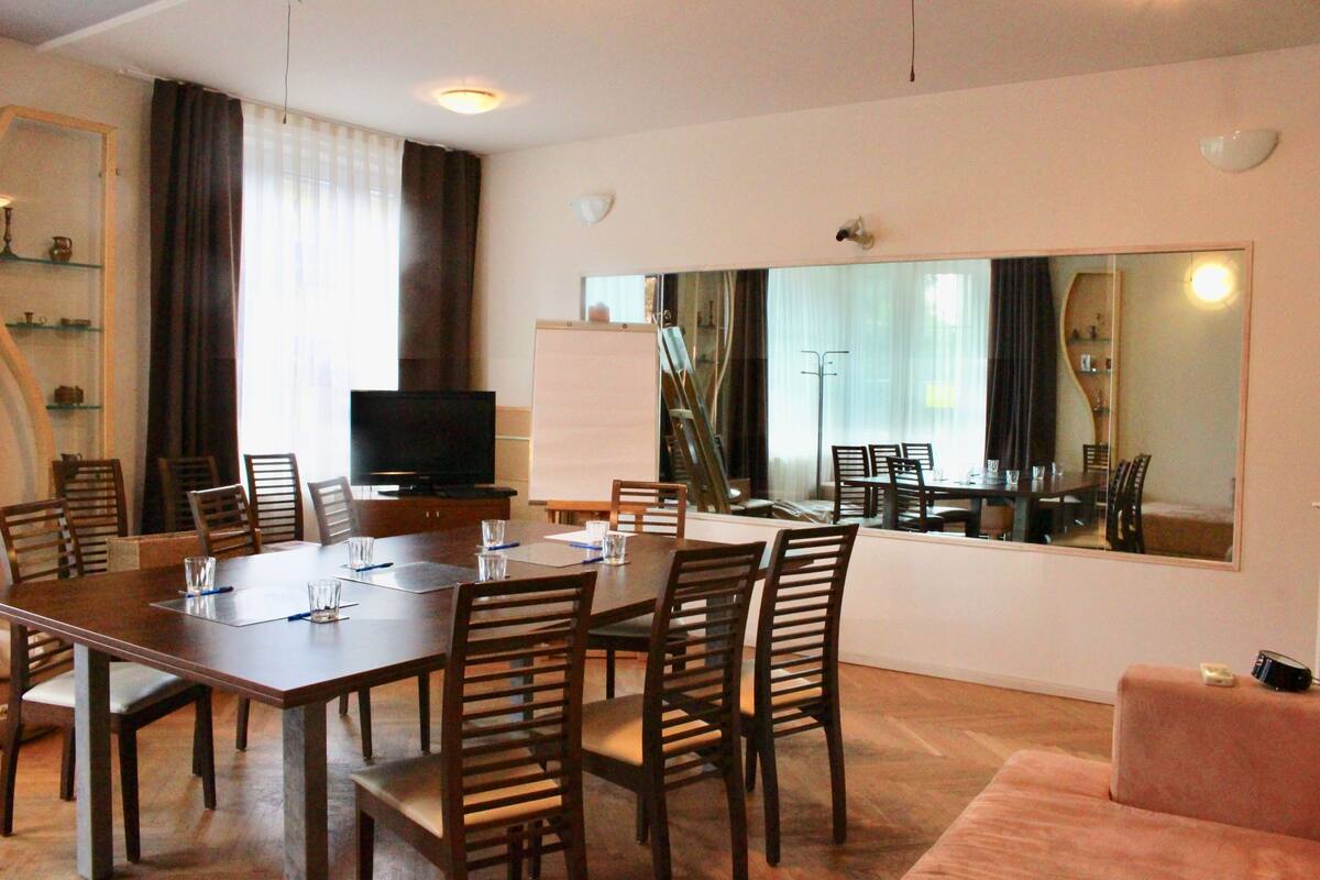A conference room with a large table, chairs, a television, and a large mirror.