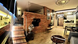 Un intérieur moderne avec un mur d’accent en briques, un escalier menant à un niveau supérieur, un coin repas et une cuisine.