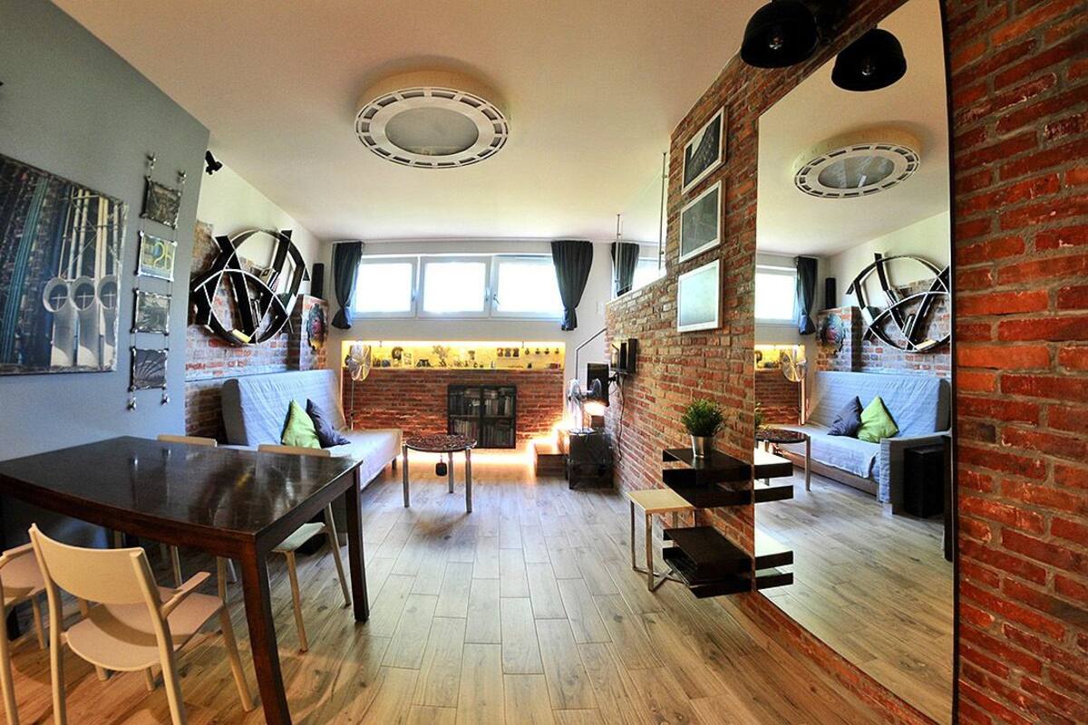 A spacious living area with a brick wall, a fireplace, and a dining table with chairs.