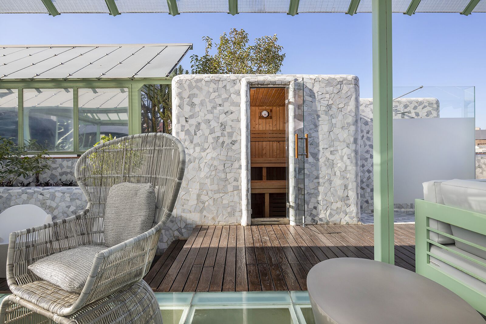 A wooden deck with a wicker chair and a cushioned bench.