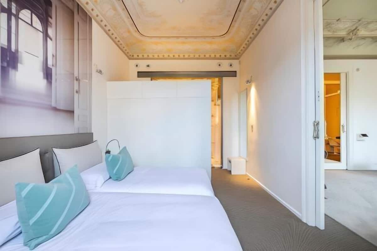 Une chambre d’hôtel avec un grand lit, une armoire et une porte donnant sur une autre pièce.