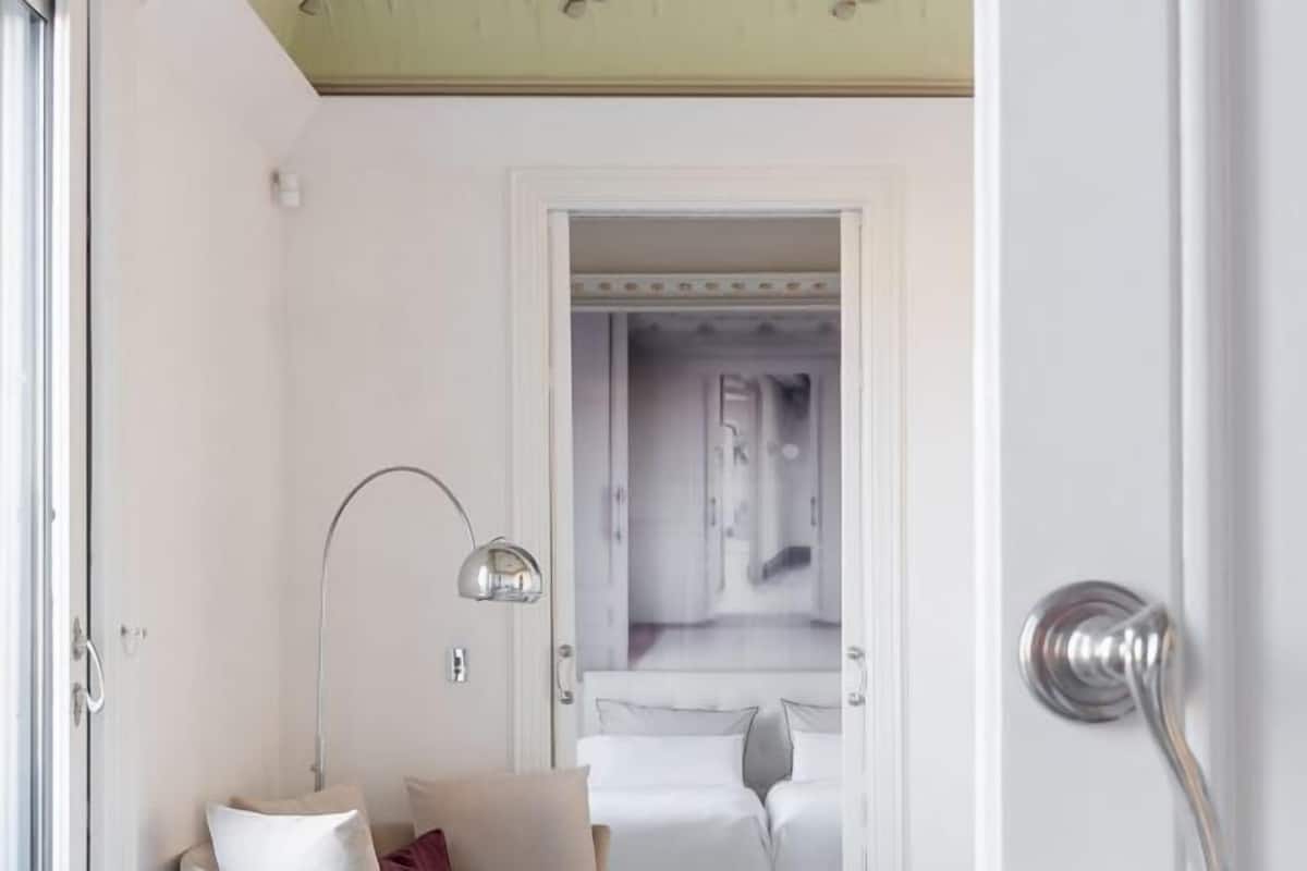 Une chambre d’hôtel avec un lit, une lampe de chevet et une porte donnant sur une salle de bain.