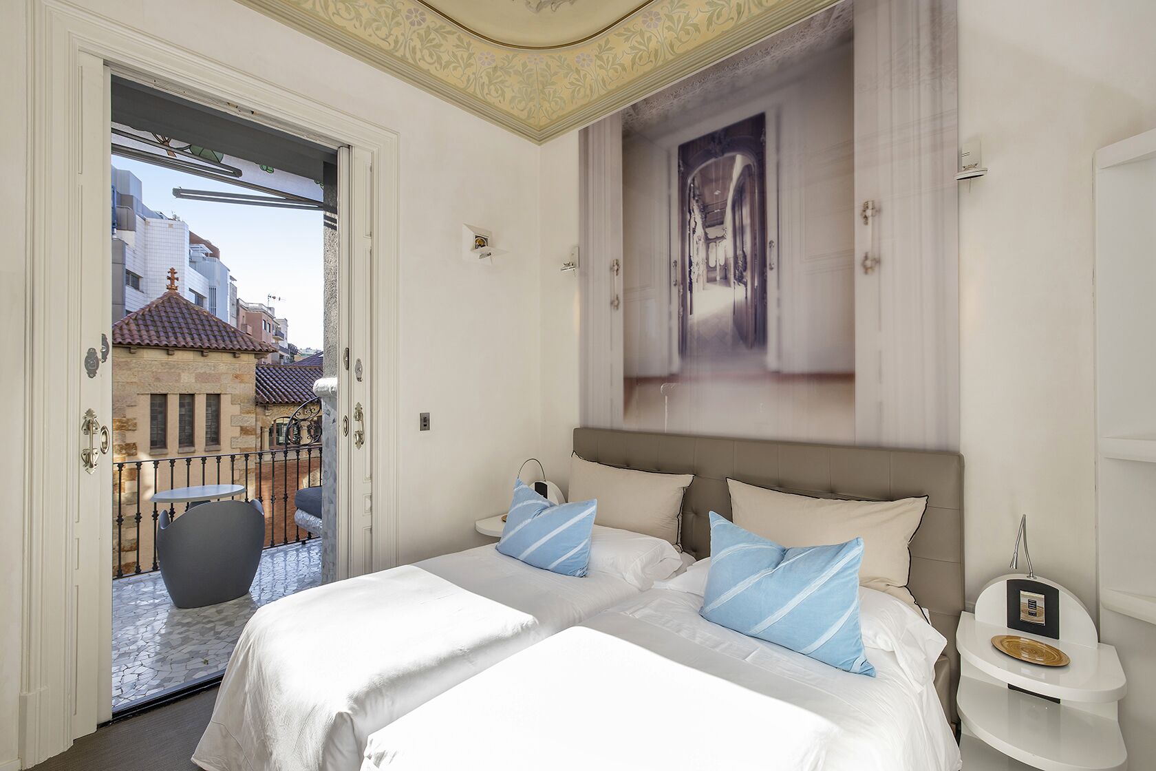 A hotel room with a large bed, a nightstand, and a view of a city street.