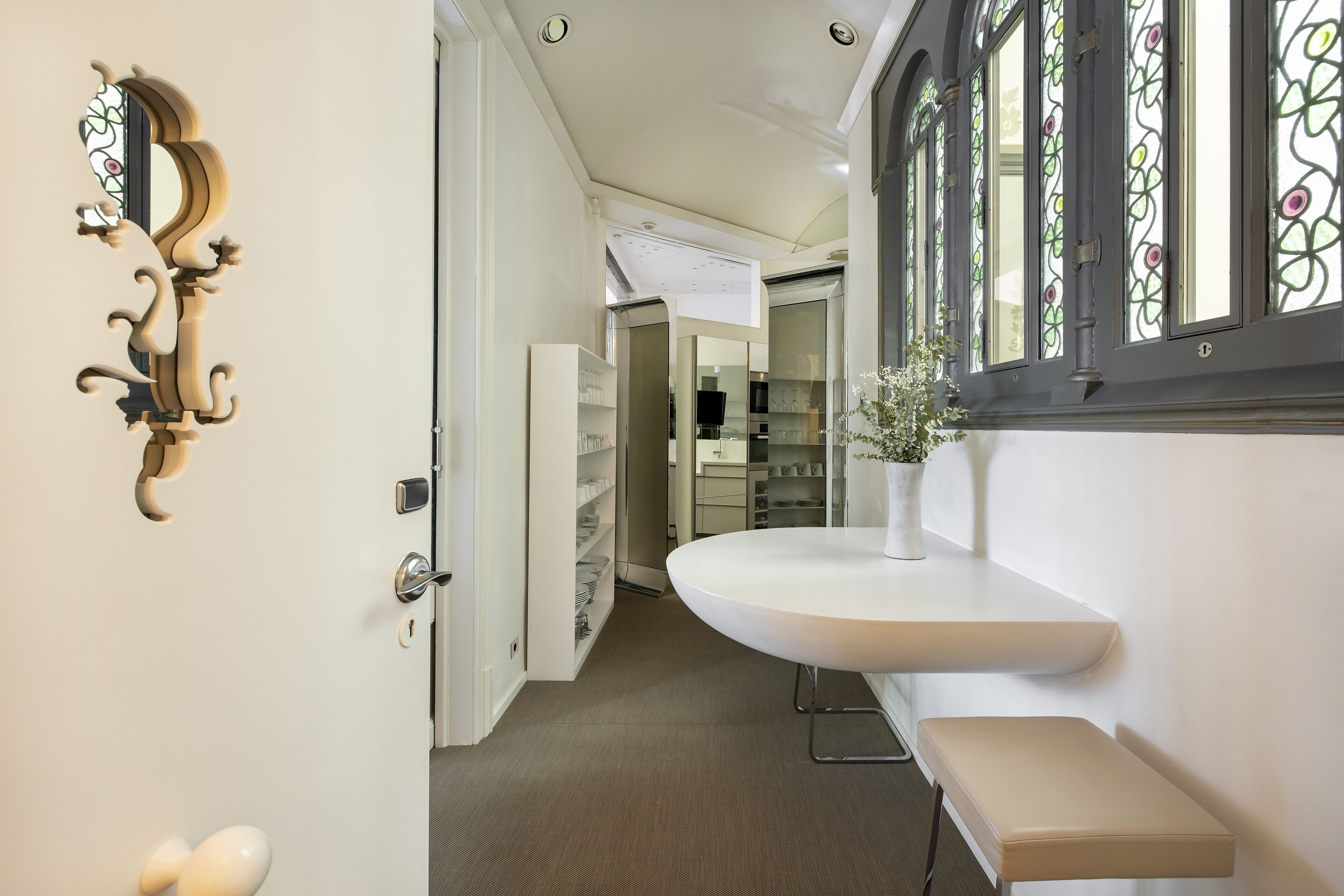 A hallway with a white door, a white bench, and a white counter.