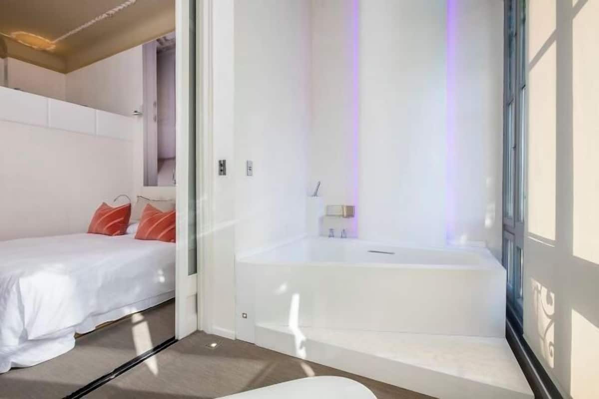 Une chambre moderne avec un lit, une douche à l’italienne et une vue sur l’extérieur.