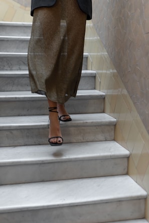 A person descending a marble staircase with a tiled wall on one side.