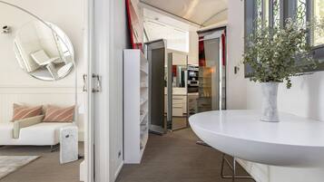 A modern interior with a white sofa, a round mirror, a white table, and a potted plant.